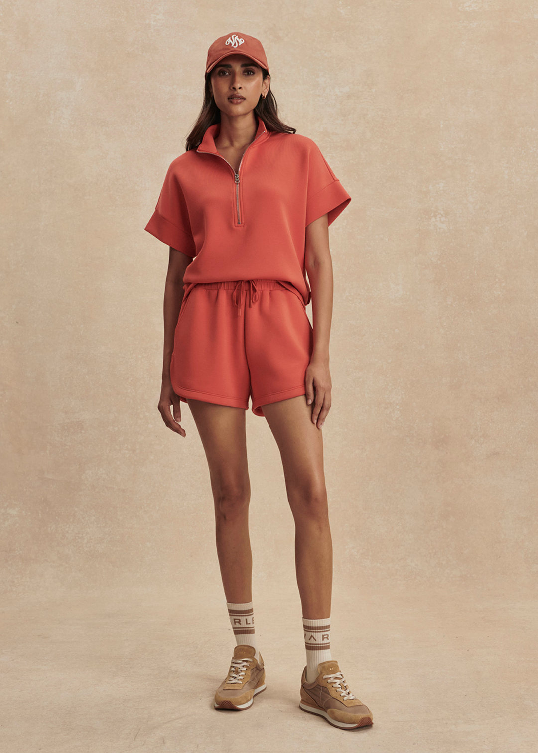 Woman wearing orange shorts with a half zip top