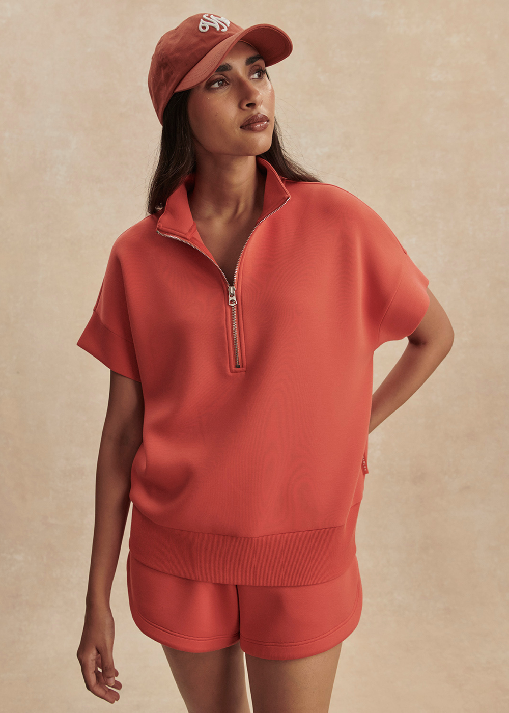 Woman wearing an orange half zip top with matching shorts