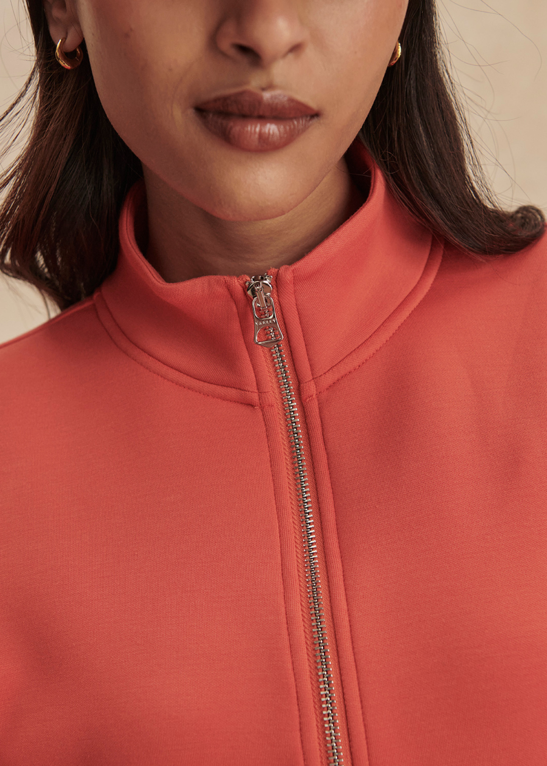 Close up of a woman wearing an orange half zip top