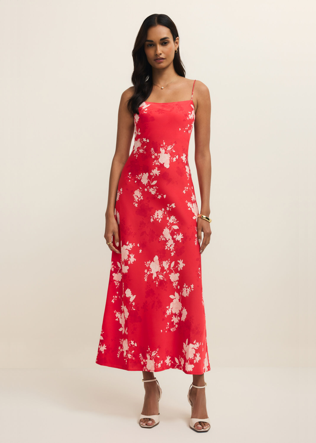 Woman wearing a red and white floral maxi dress against a white background