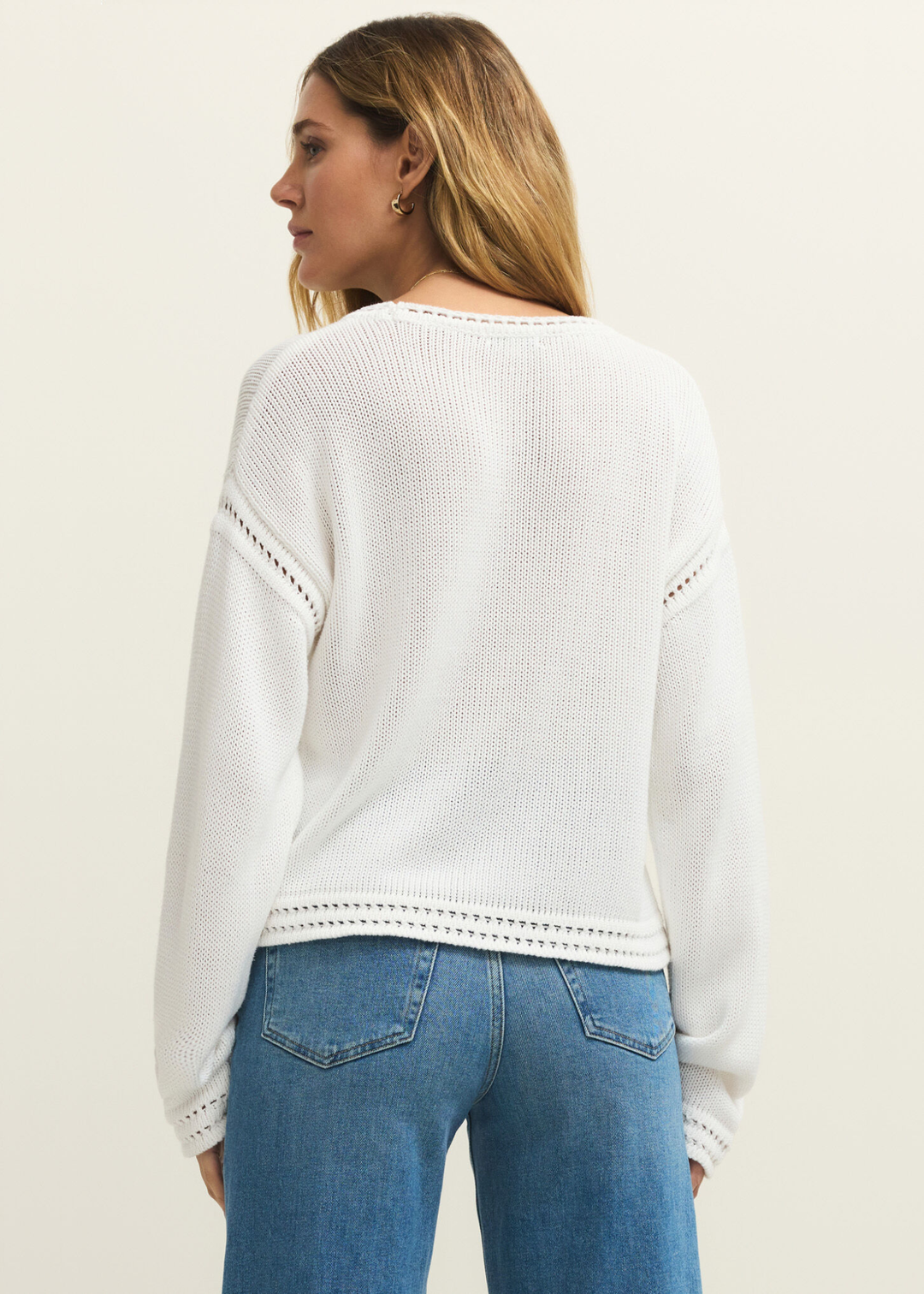 Woman turned around wearing a white sweater with jeans