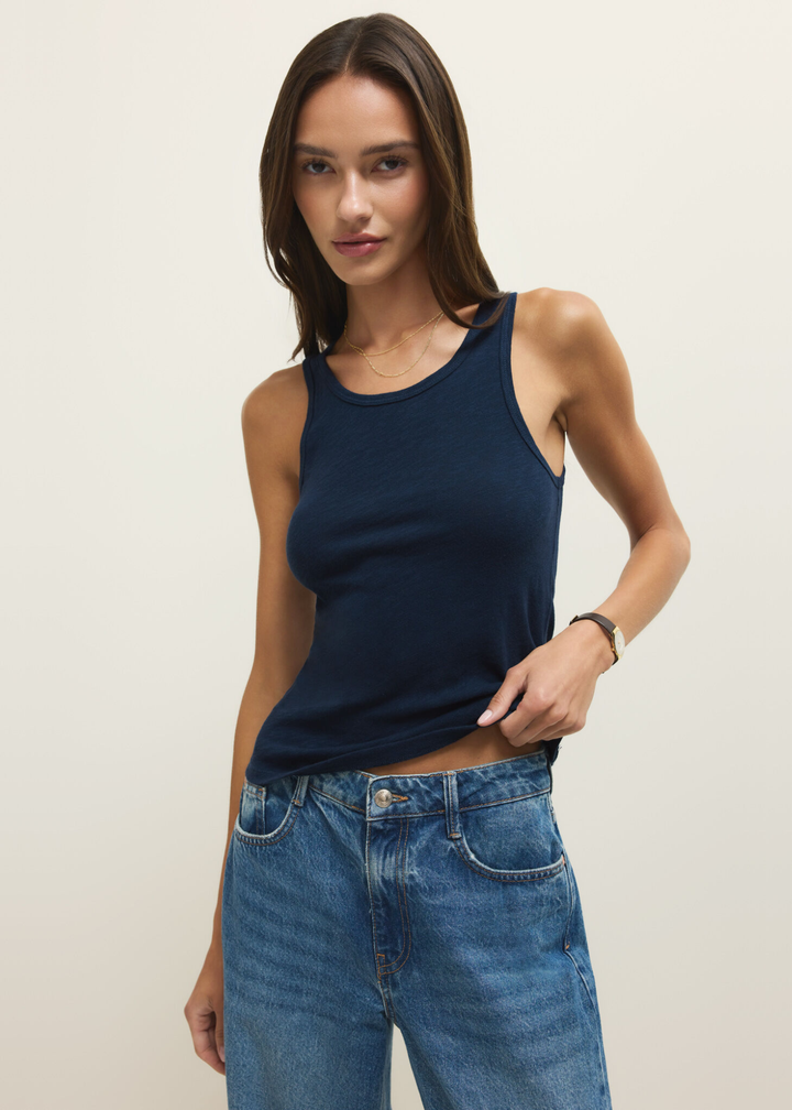 Woman wearing a navy tank top with jeans against a white background