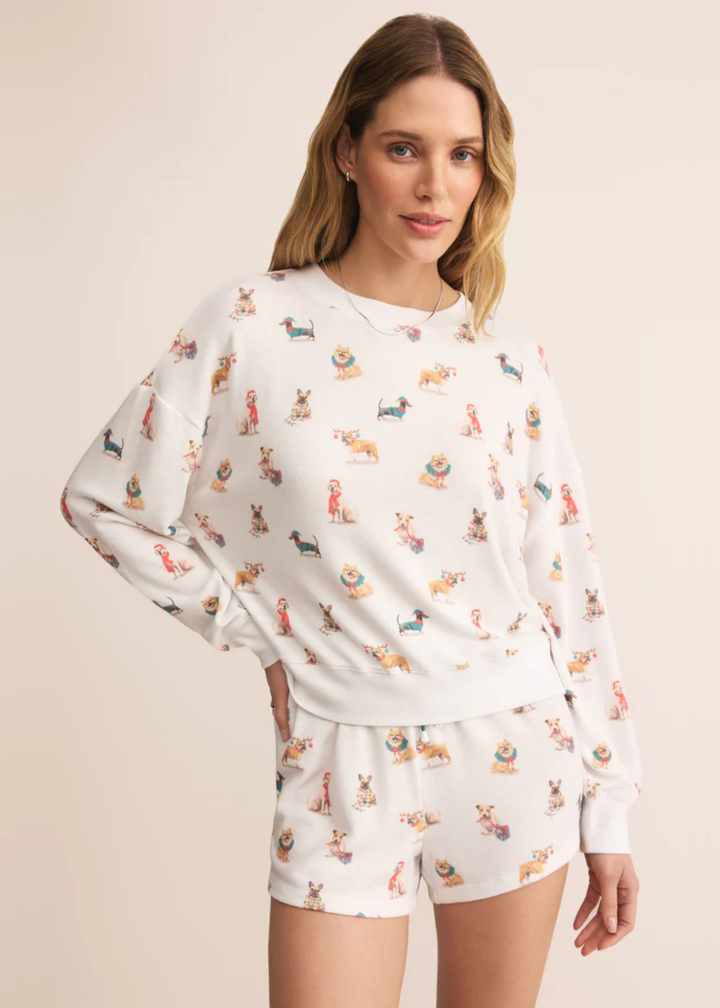 Woman wearing a white long sleeve shirt with a Christmas dog pattern and matching shorts in front of a tan background