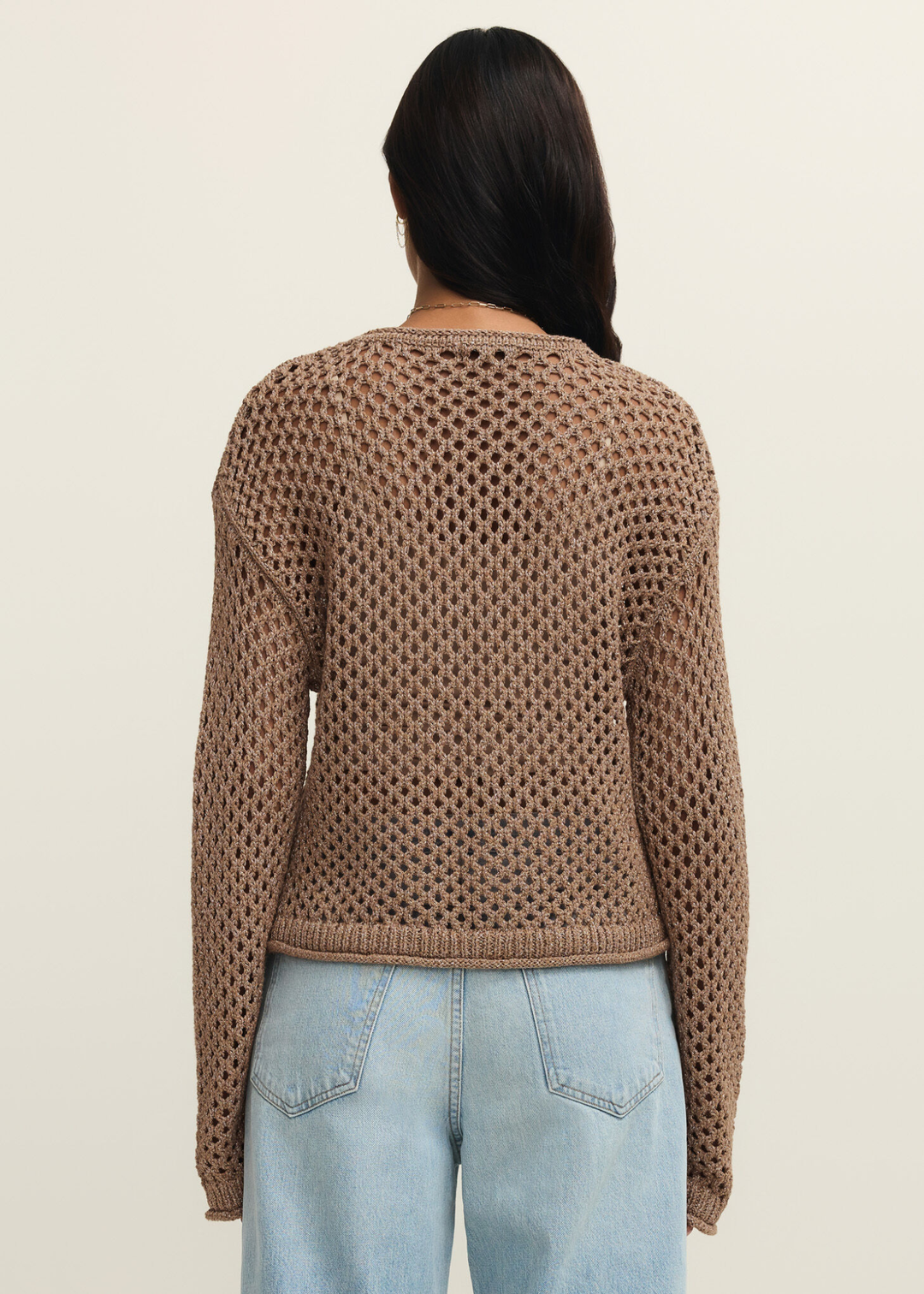 Woman turned around wearing a brown shimmer sweater with jeans