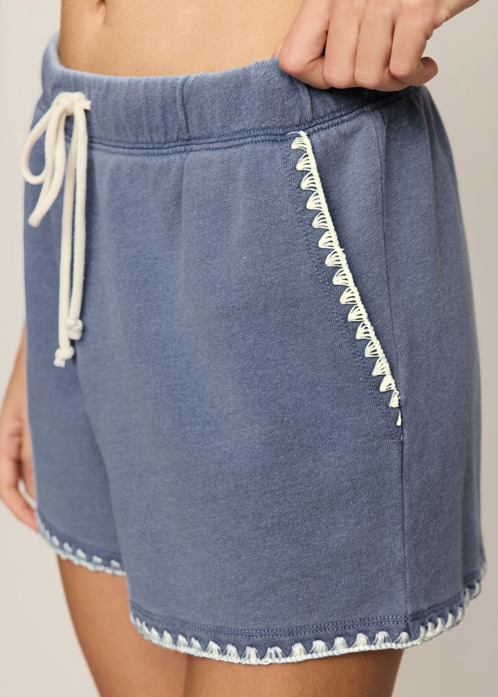Woman wearing blue knit denim shorts with white whipstitch