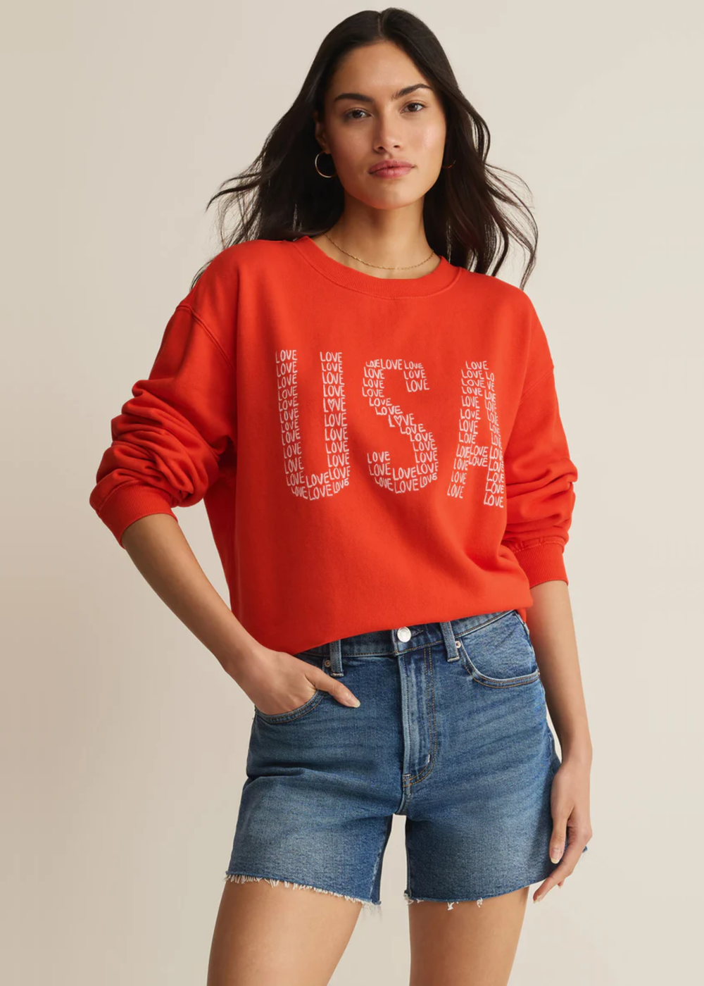 Woman wearing a red sweatshirt with a "USA" graphic and "love" lettering with denim shorts