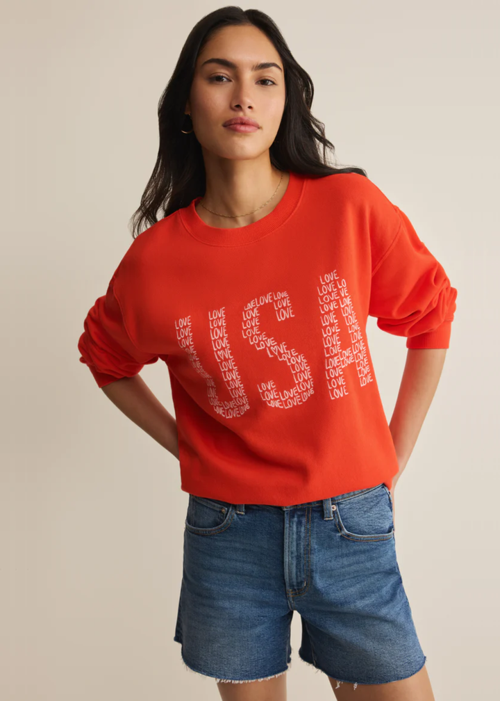 Woman wearing a red sweatshirt with a "USA" graphic and "love" lettering with denim shorts