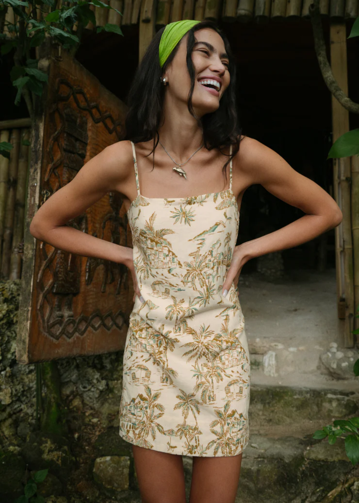 Woman wearing a cream mini dress with a tropical print