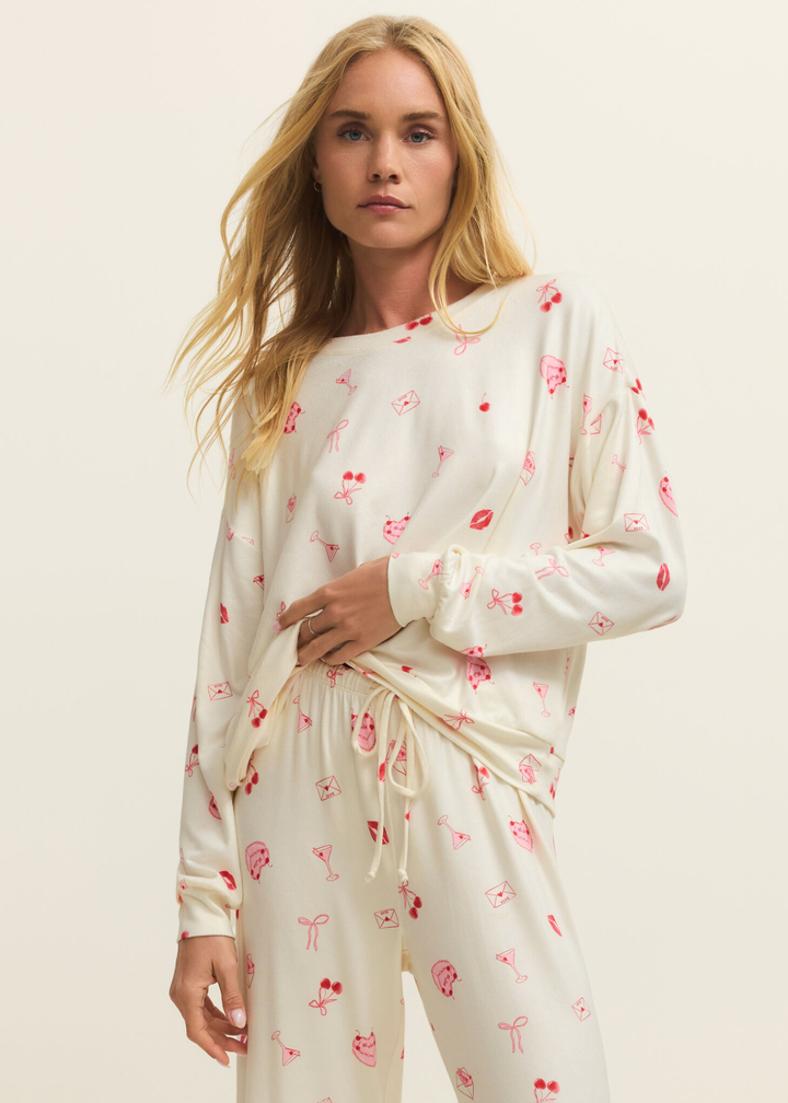Woman wearing a white pj set with a pink and red graphic pattern