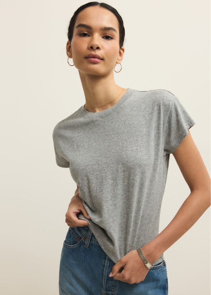Woman wearing a grey short sleeve t-shirt and jeans against a grey background