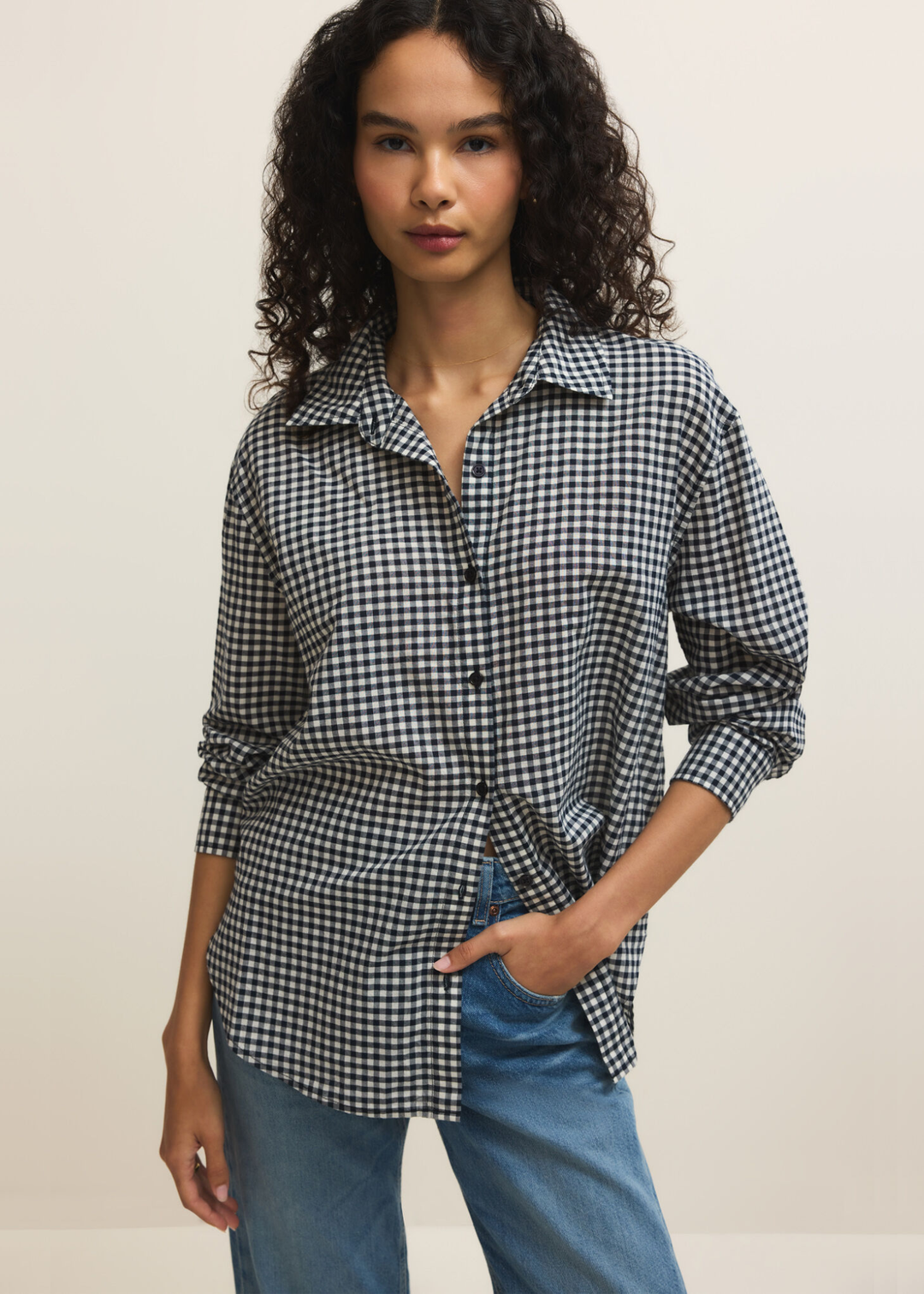 Woman wearing a navy and white gingham button down with jeans