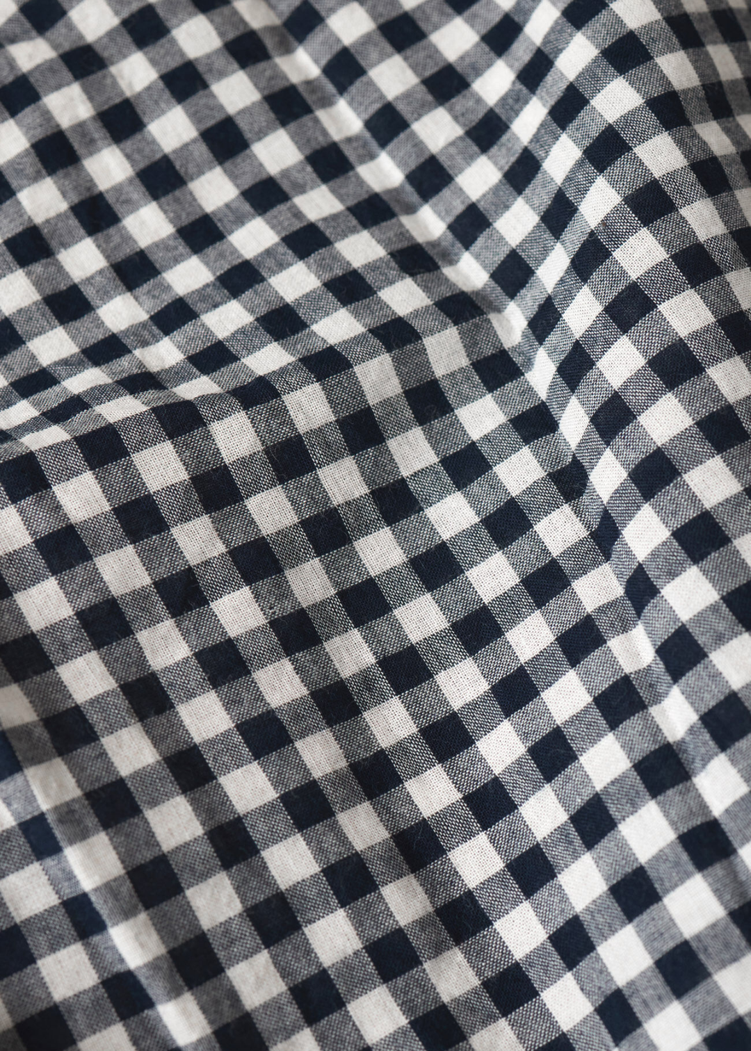 Close up of the fabric of a navy and white gingham button down