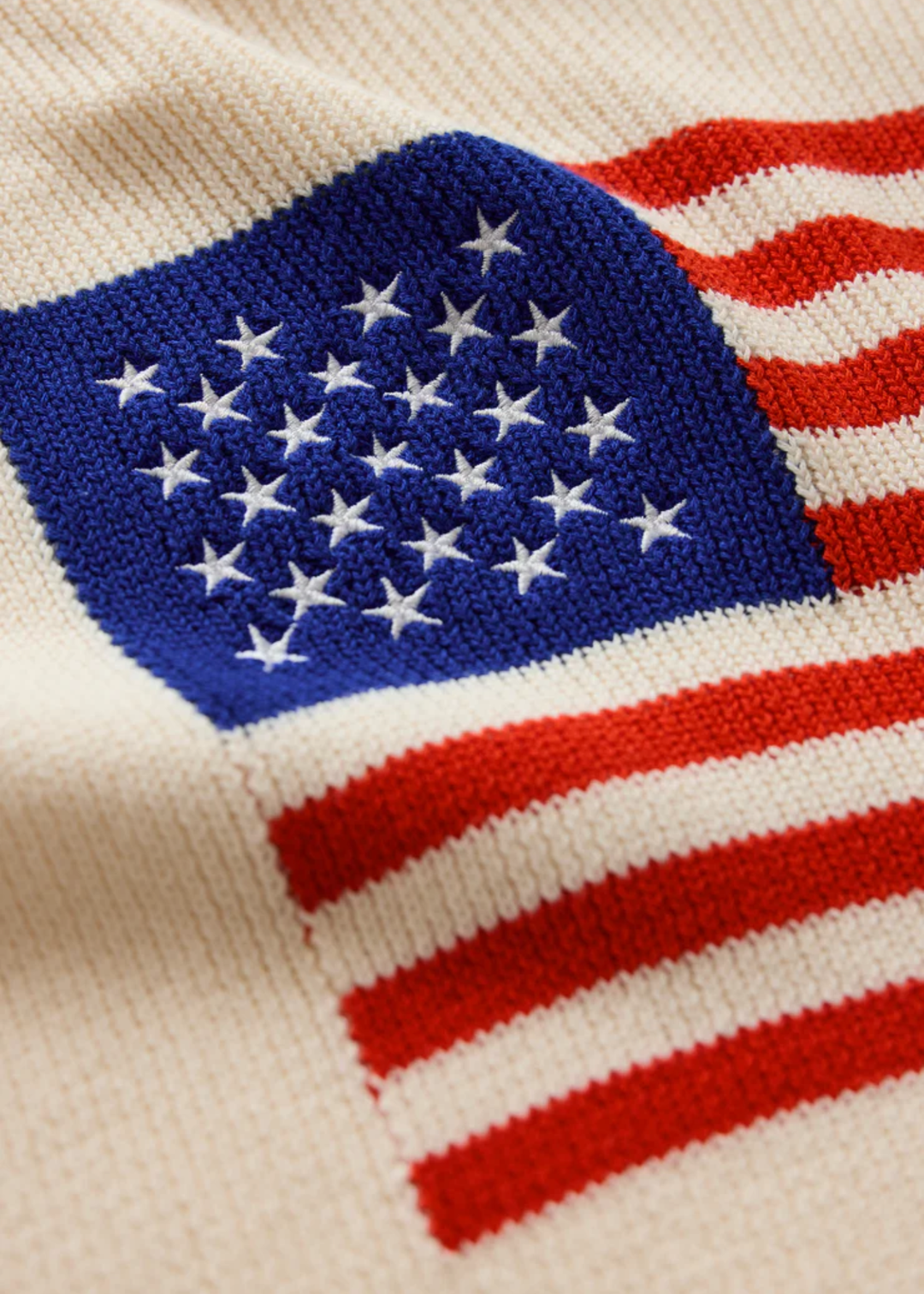 Close up of a cream sweater with an American flag graphic