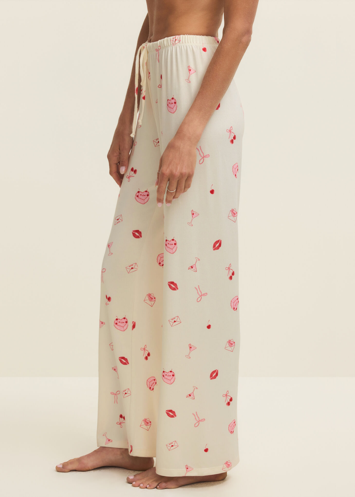 Woman turned to the side wearing white pajama pants with a pink and red graphic pattern