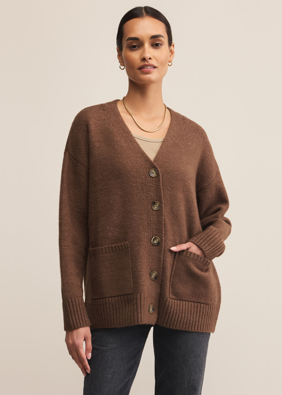 Woman wearing a brown button down cardigan against a grey background