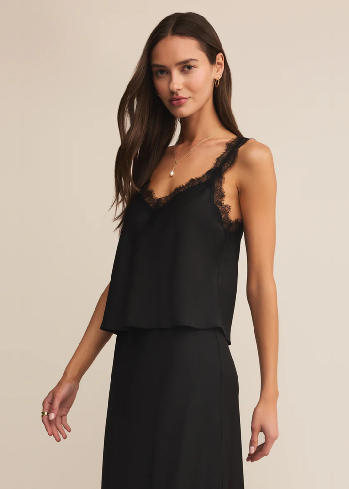 Woman wearing a black satin cami with black lace trim with a matching skirt