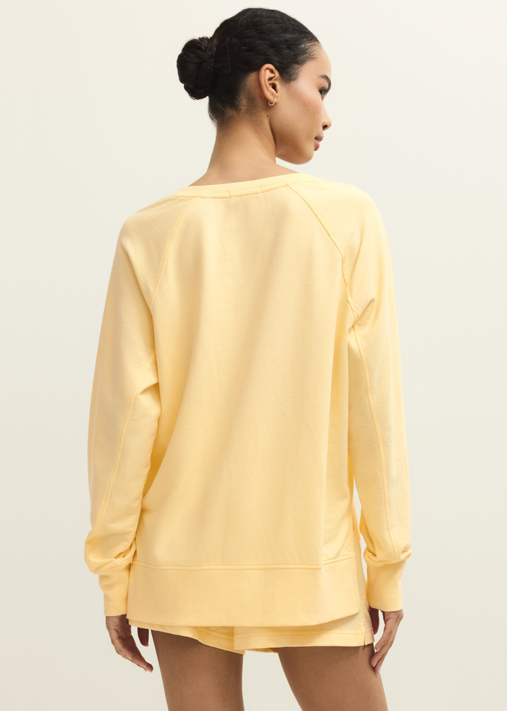 Woman turned around wearing a yellow v-neck sweatshirt with yellow shorts