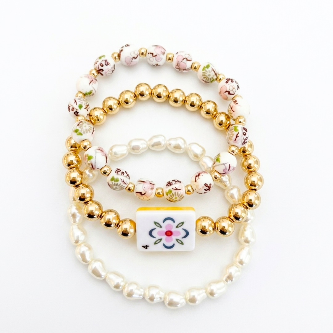 Set of beaded bracelets with floral charm on a white background