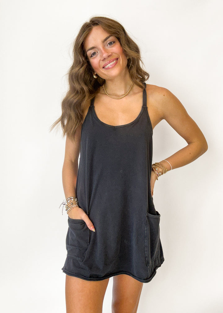 A woman modeling a dark charcoal gray sleeveless tank dress with side pockets, posed against a plain white background.