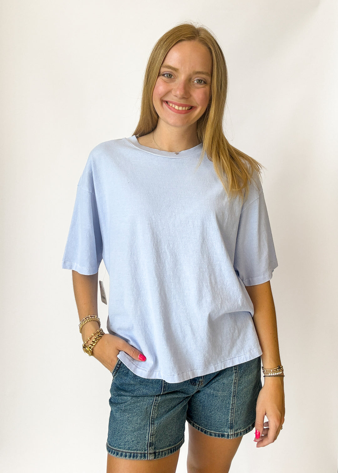 Woman wearing a light blue t-shirt and denim shorts against a white background