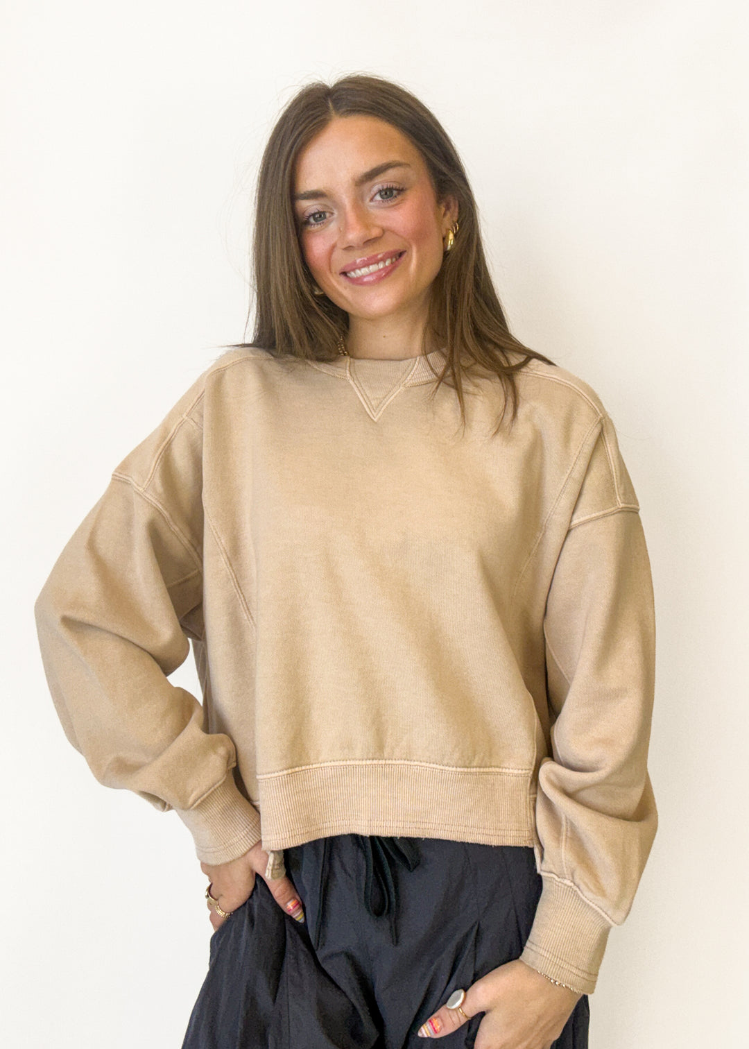A woman wearing a beige oversized crewneck sweatshirt 