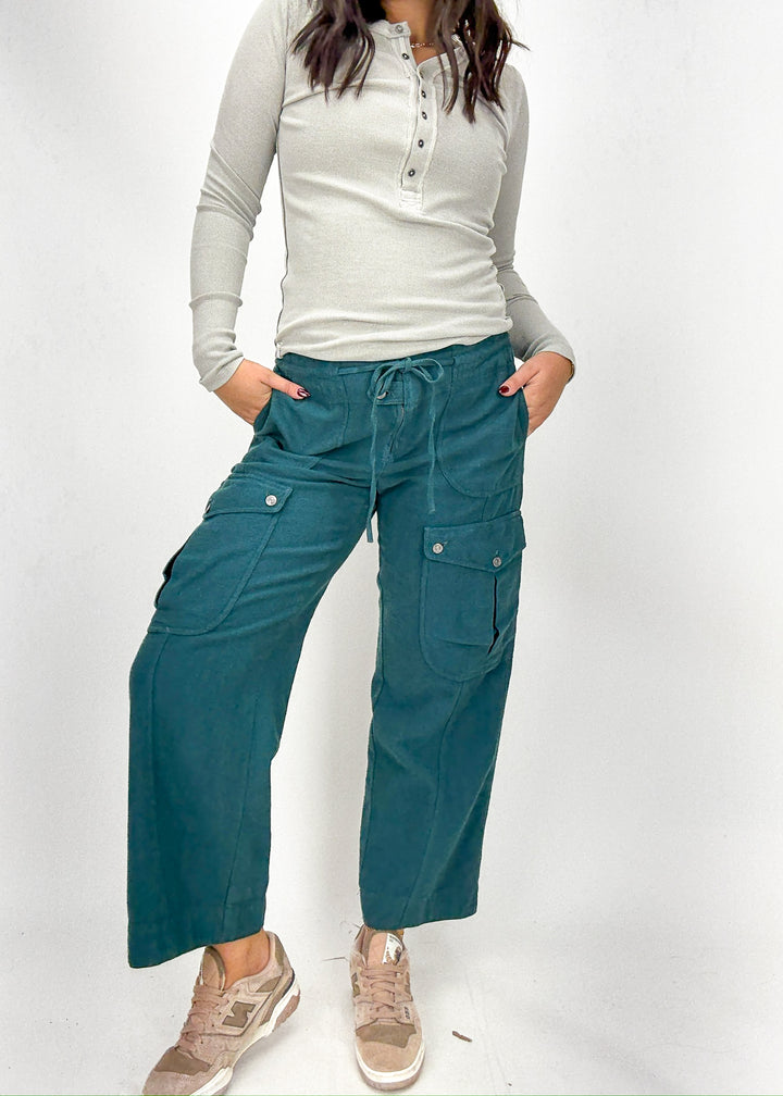 Person wearing teal cargo pants and a white long-sleeve shirt 