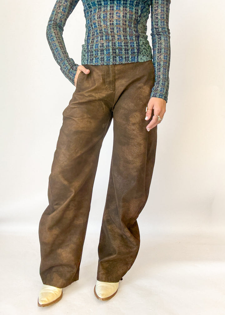 A model wearing brown wide-leg trousers with a textured, slightly distressed finish, 