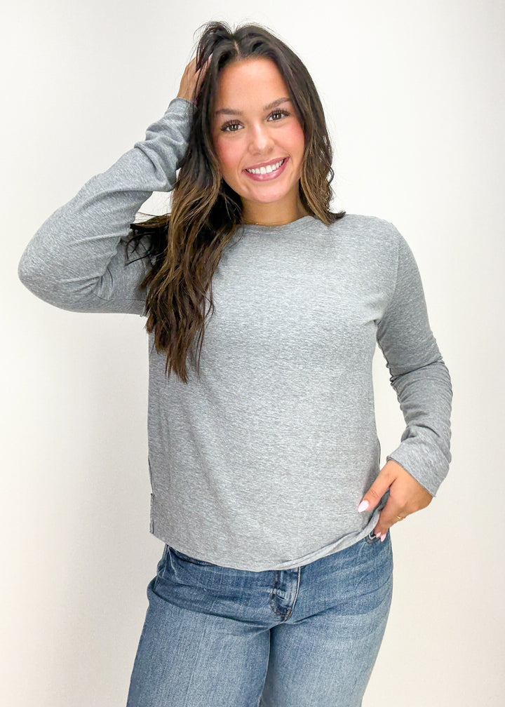 Woman wearing a gray long-sleeve top and blue jeans
