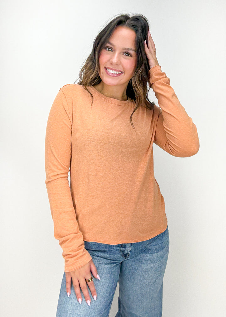 Woman wearing a mustard yellow long-sleeve top and blue jeans 