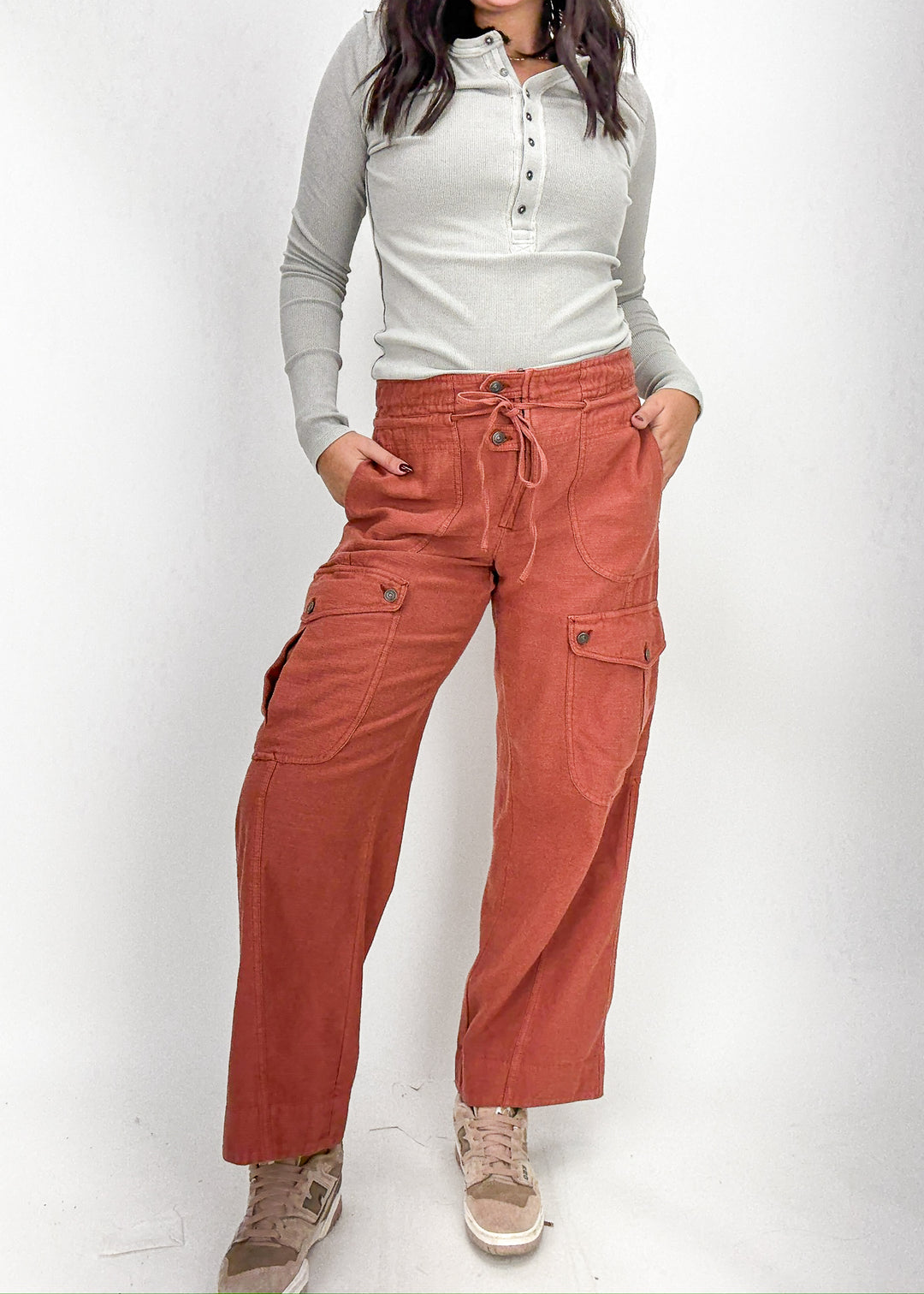 Person wearing rust-colored pants and a light gray long-sleeve shirt 