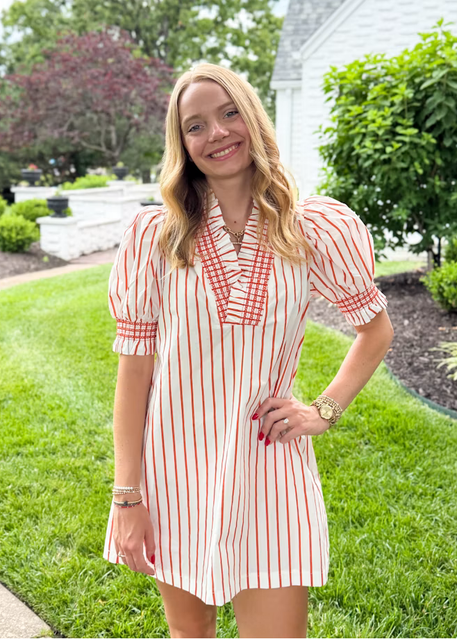Woman in a orange and white striped dress standing in a garden