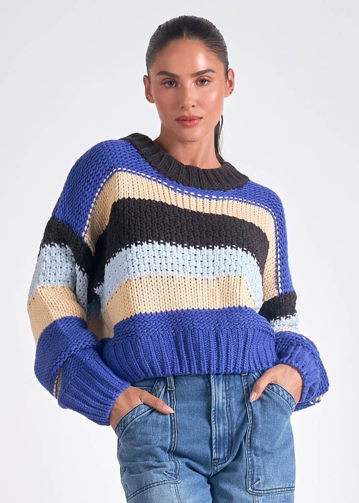 A women's knit sweater featuring bold multi-color stripes in blue, black, beige, and light blue, perfect for a casual yet stylish look.