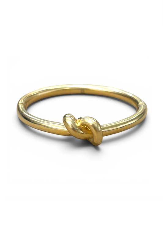 A gold ring with a knotted detail at the front, photographed on a clean white background.