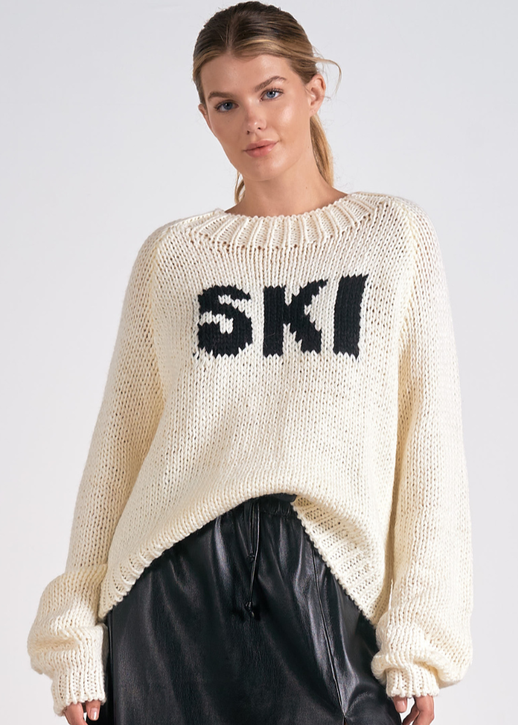 A cozy oversized knit sweater featuring bold black "SKI" text on the front, perfect for winter fashion and casual wear.