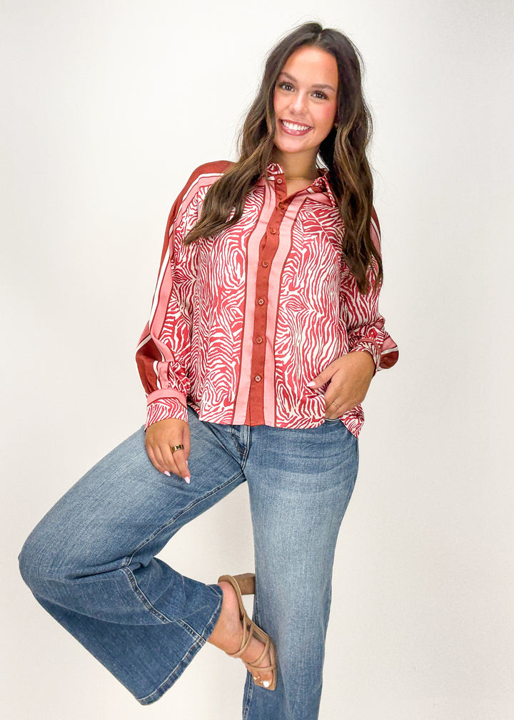 Woman wearing a red patterned shirt and blue jeans 