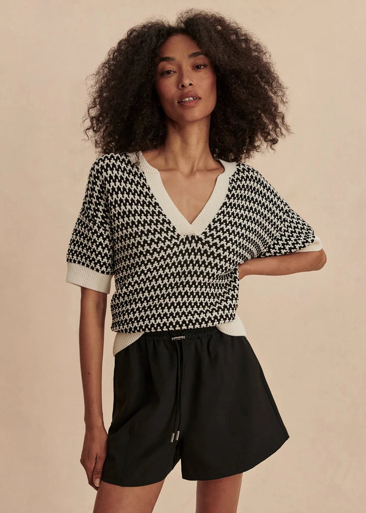 Woman wearing a black and white patterned top with a beige background