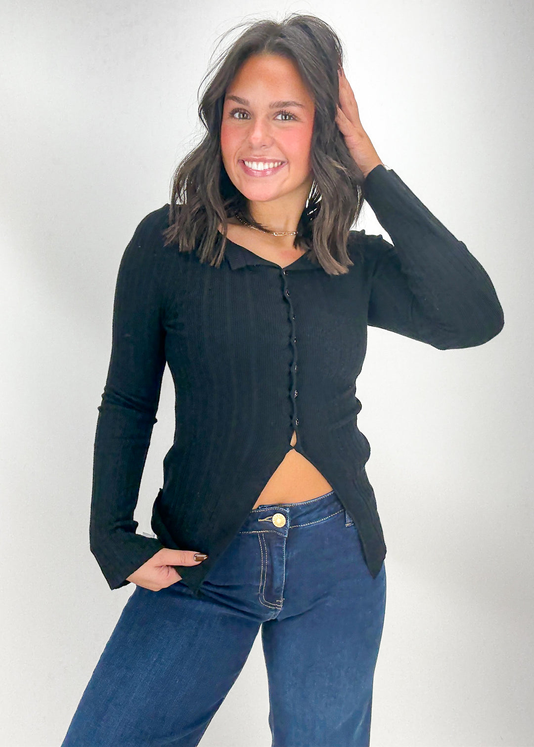 Woman wearing a black long-sleeve top and blue jeans 