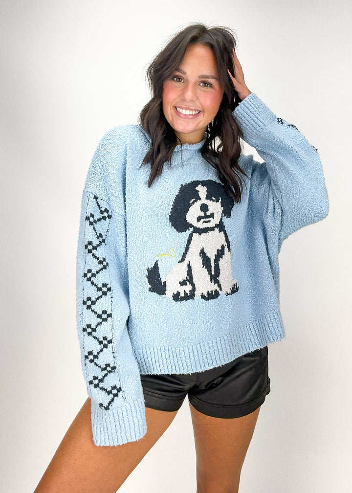 Woman wearing a light blue sweater with a dog design 