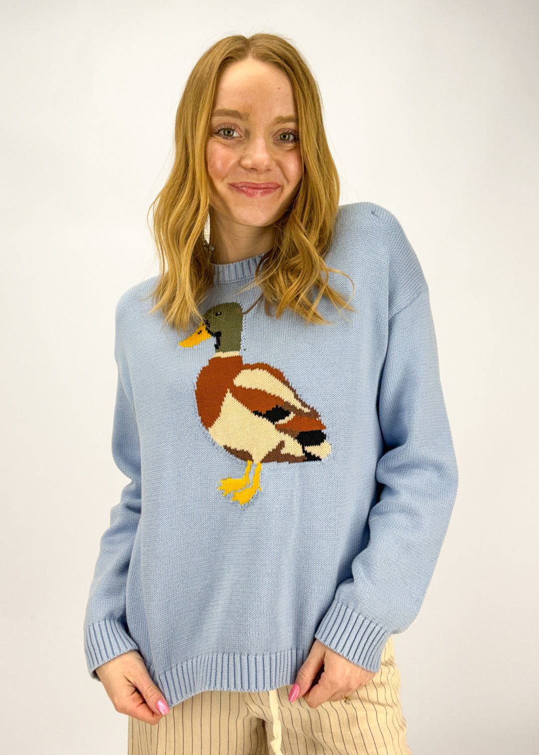 Woman wearinb blue sweater with a duck graphic on it. 