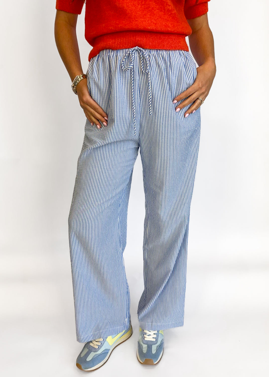 Person wearing blue striped pants and a red top on a white background