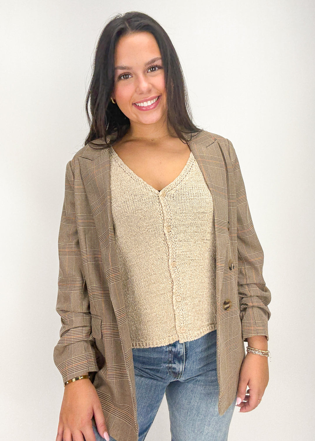Woman wearing a beige cardigan over a beige sweater with blue jeans 
