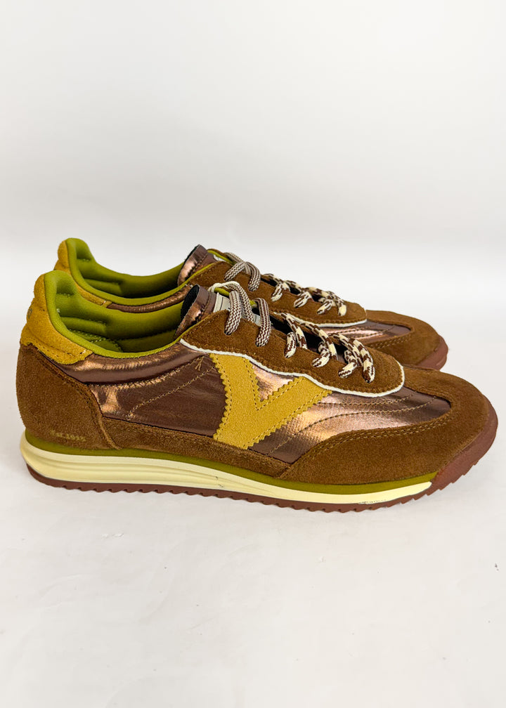 A pair of vintage-style low-top sneakers in brown suede and metallic bronze leather, featuring olive green accents on the collar lining, side panel, and midsole, with cream-colored laces and a white midsole.
