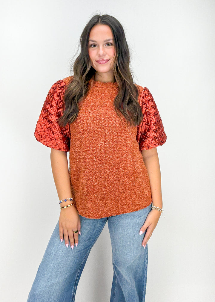 Woman wearing a rust-colored top with puff sleeves 