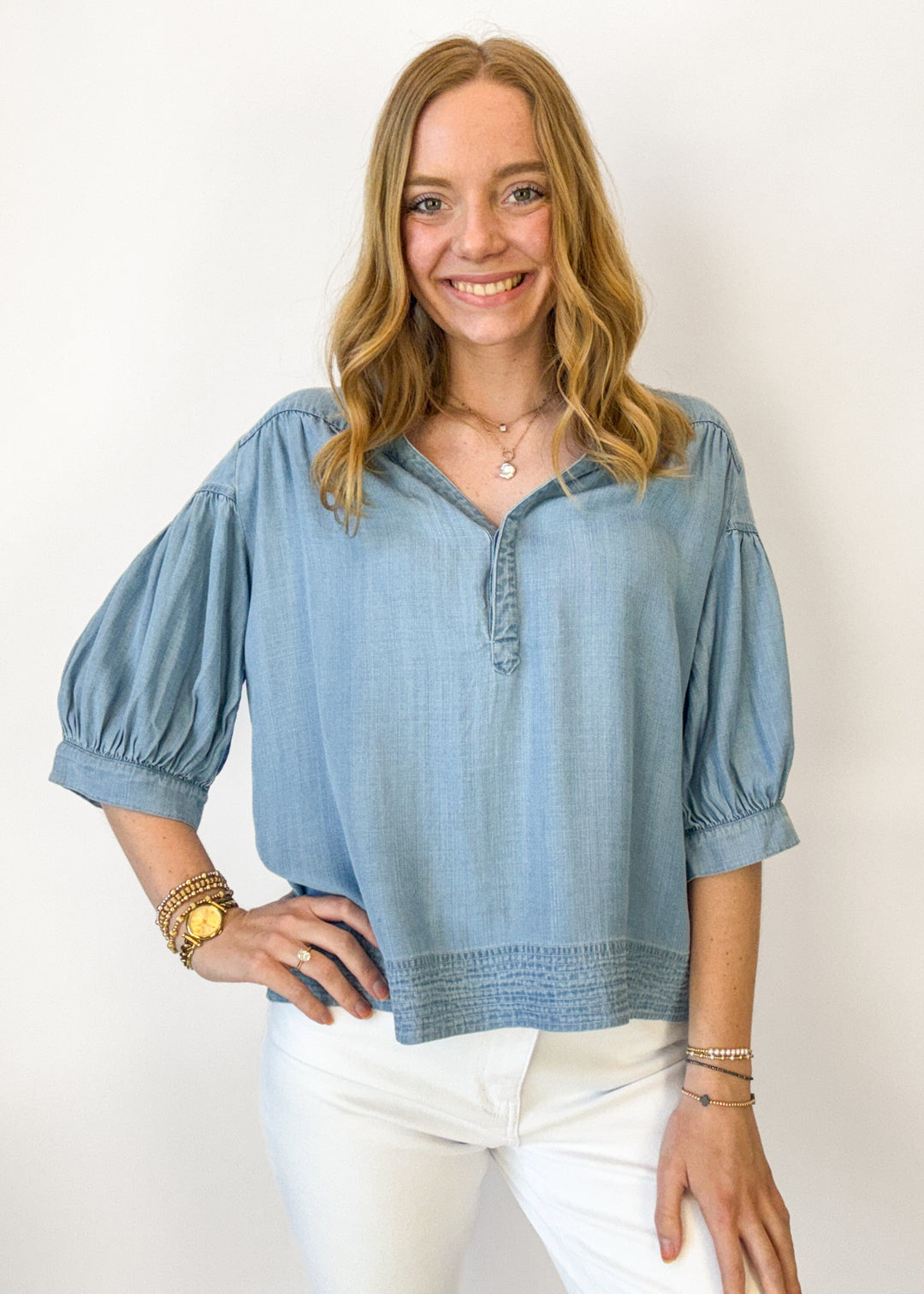 Woman wearing a light blue blouse with puff sleeves against a white background
