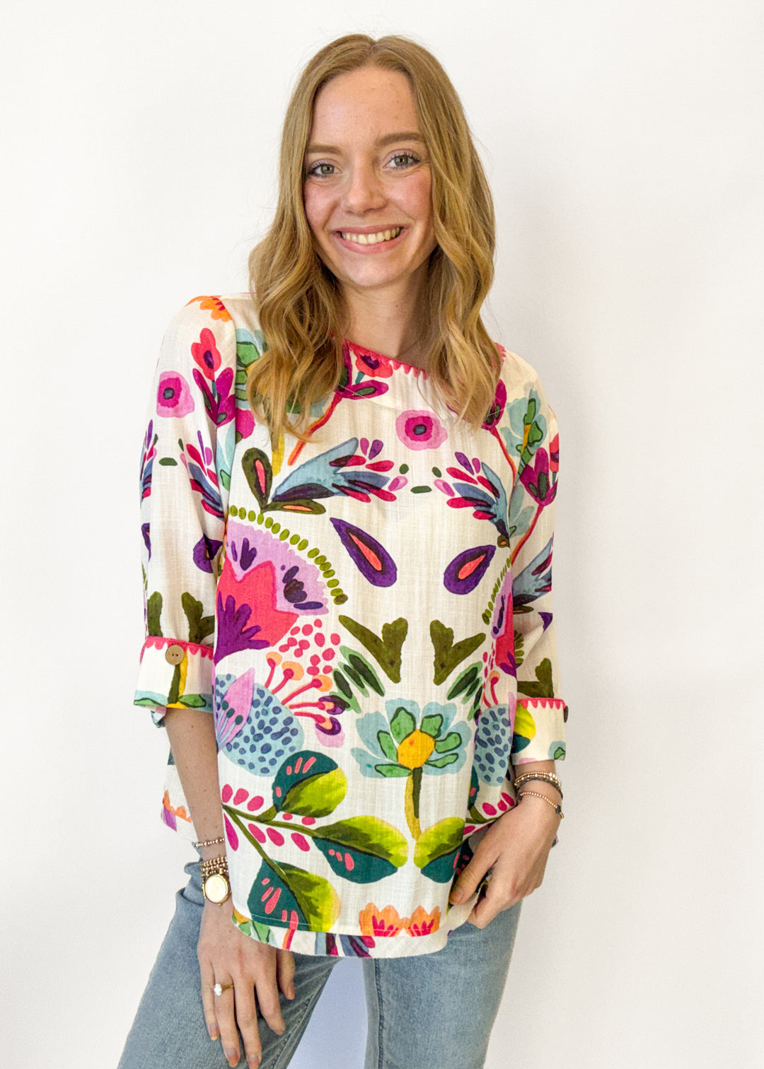 Woman wearing a colorful floral-patterned top against a white background