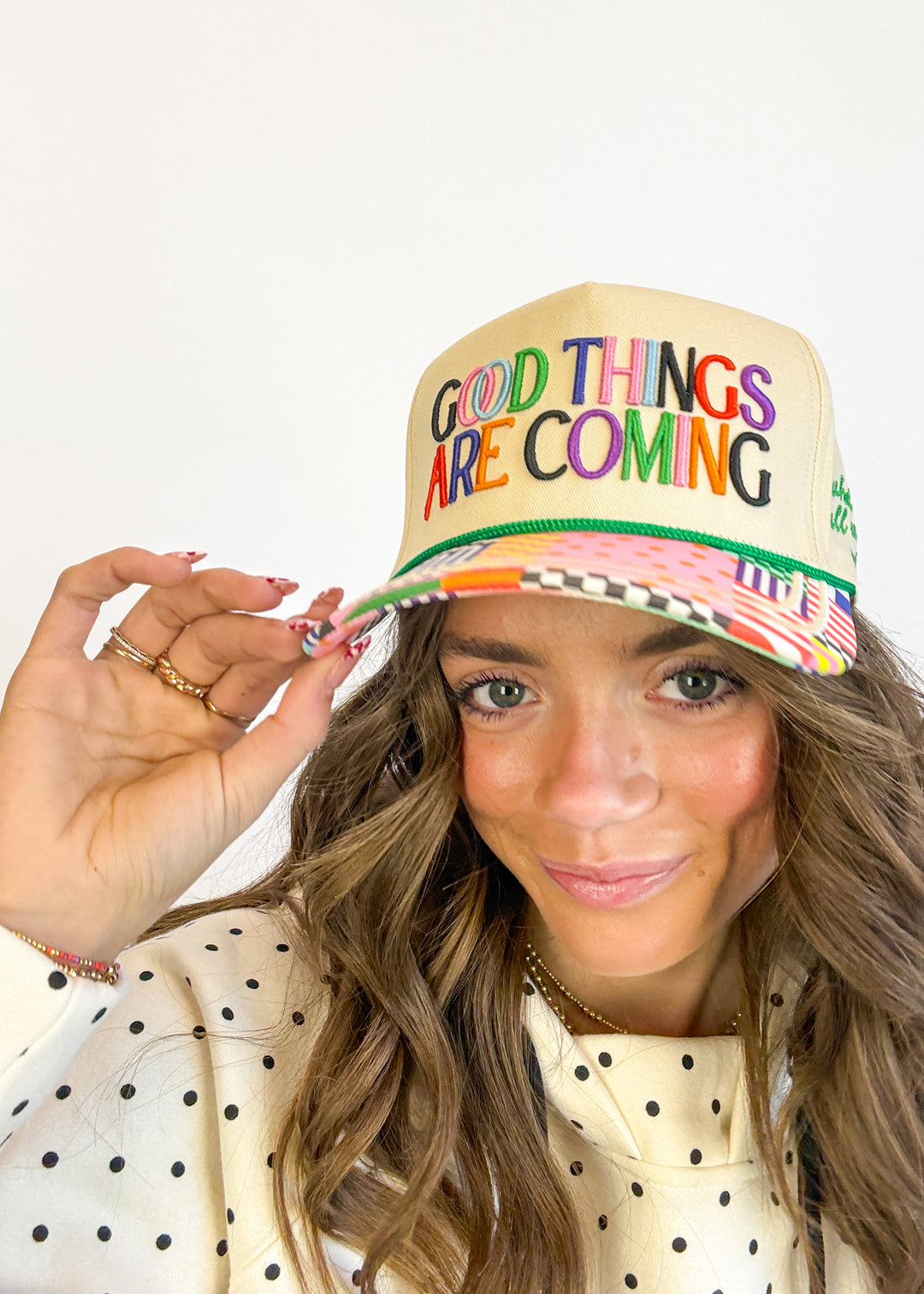 Person wearing a colorful cap with 'Good Things Are Coming' text on a white background