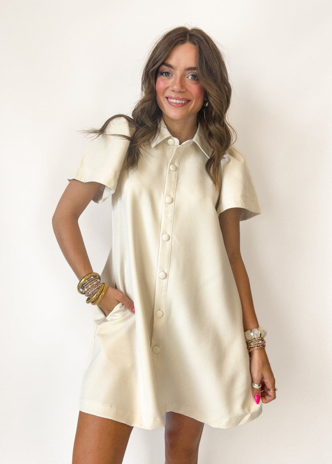 Woman wearing a cream-colored shirt dress on a white background