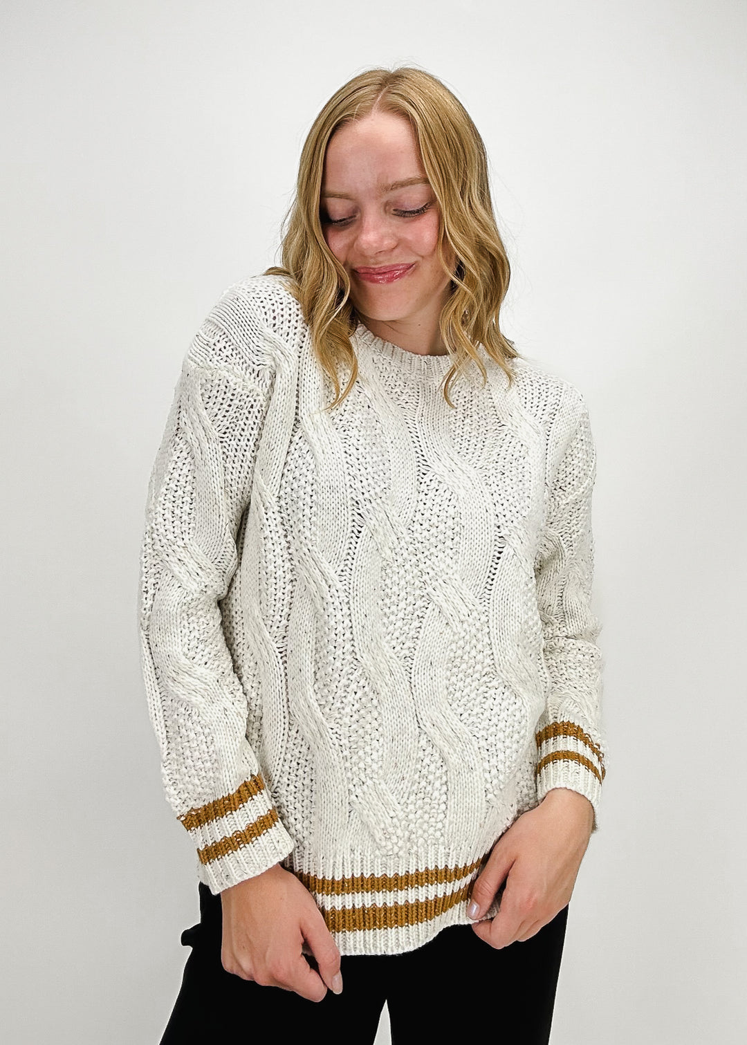 white cable knit sweater with burnt orange gold varsity stripe details on sleeves