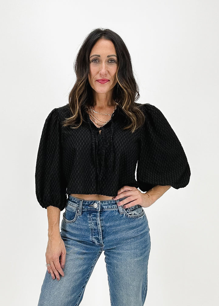 women's black textured crop top with puff sleeves and chest bow details