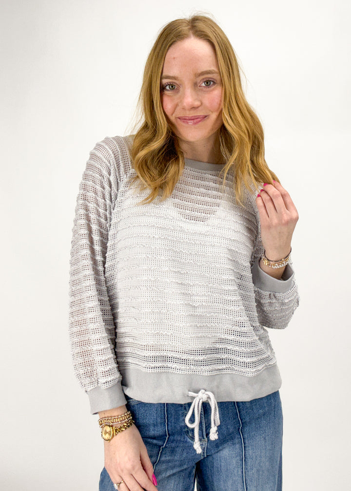 Woman wearing a gray sweater and blue jeans on a white background